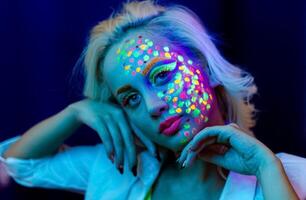 Porträt von ein Frau mit gemalt Gesicht, Frau mit uv bilden im Studio, Porträt von ein Frau im Karneval Maske, das Frau ist dekoriert im ein ultraviolett Pulver foto