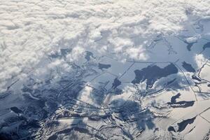 luftaufnahme über wolkenoberseite zu schneebedeckten flüssen, feldern und straßen, winterfrische frostige luft foto