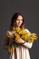 Porträt von ein Mädchen mit ein Strauß von Mimose, Frühling Stimmung, Mutter Tag foto