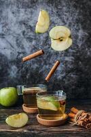 Apfel Apfelwein trinken mit Zimt und frisch Äpfel auf dunkel hölzern Hintergrund. foto
