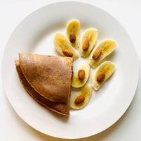 Pfannkuchen mit Banane und Mandeln auf ein Weiß Teller auf ein Weiß Hintergrund foto