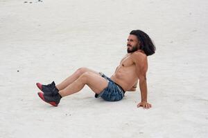 jung muskulös Mann ausüben auf das Strand, jung muskulös Mann tun Körperbau Übungen auf das Strand, sportlich jung Mann auf das Strand foto