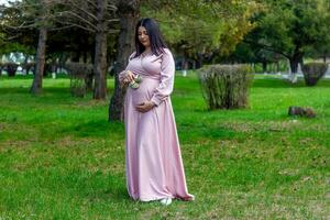 das schwanger Frau im das Park, schön Frau im das Park, schwanger Frau im Frühling foto