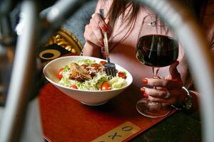 Frau Sitzung beim Tabelle mit Salat und Wein foto