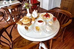 Weiß Tabelle einstellen mit Platten von Essen und Tassen von Kaffee foto