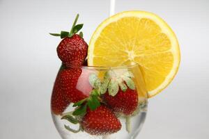 ein Glas von Wasser mit Erdbeeren und ein Orange Scheibe foto