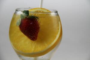 ein Glas von Wasser mit Erdbeeren und ein Orange Scheibe foto