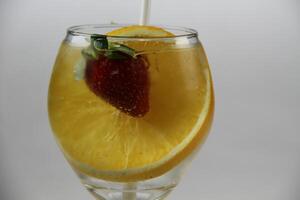 ein Glas von Wasser mit Erdbeeren und ein Orange Scheibe foto