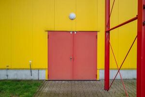 groß rot Metall Tür im Gelb Haus Mauer foto