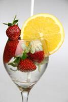 ein Glas von Wasser mit Erdbeeren und ein Orange Scheibe foto
