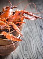 Schüssel von gekocht Flusskrebs auf das hölzern Tabelle foto