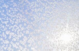 abstrakt Winter Hintergrund. Frost auf ein gefroren Fenster gegen das Blau Himmel. foto