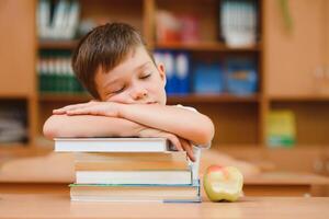 Porträt von süß Junge auf oben von Buch Stapel. das Konzept von Lernen im primär Schule. foto