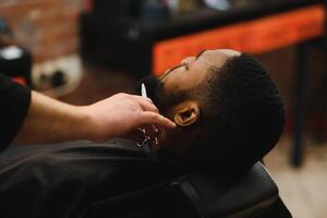 afrikanisch männlich Klient bekommen Haarschnitt beim Barbier Geschäft von Fachmann Friseur. foto