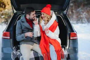 süß Paar haben Winter Wald Picknick Trinken Tee von Tee nehmen Weg Tasse. Natur Picknick. Liebe Geschichte Datum beim Wagen. foto