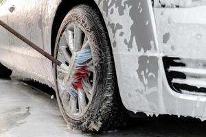 Waschen Luxus Silber Auto auf berührungslos Auto waschen. Waschen Limousine Auto mit Schaum Selbstbedienung und hoch Druck Wasser. Reinigung das Einzelheiten von Wagen. Sauberkeit und bestellen im städtisch Umgebung foto