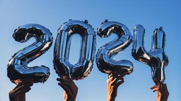 Silber vereiteln Nummer 2024 Feier Neu Jahr Ballon auf Blau Himmel Hintergrund. glücklich Neu Jahr Schöne Grüße Konzept. Hände halten Luftballons zwei tausend vierundzwanzig Jahr Weihnachten Urlaub Konzept foto