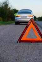 unkenntlich traurig Treiber im reflektierend Weste. männlich Treiber Stehen in der Nähe von gebrochen Auto mit öffnen oben Haube. rot Dreieck zu warnen andere Straße Benutzer von Auto Nervenzusammenbruch oder Motor Fehler halt beim Landschaft Autobahn. Notfall der Verkehr Situation foto