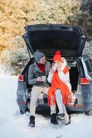 süß Paar haben Winter Wald Picknick Trinken Tee von Tee nehmen Weg Tasse. Natur Picknick. Liebe Geschichte Datum beim Wagen. foto