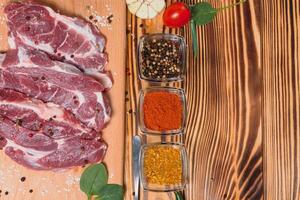 roh Schweinefleisch Fleisch mit Gewürze und Gemüse auf hölzern Tisch. foto