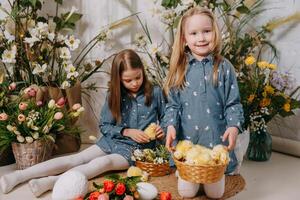 zwei Mädchen im ein schön Ostern Foto Zone mit Blumen, Eier, Hühner und Ostern Hasen. glücklich Ostern Urlaub.