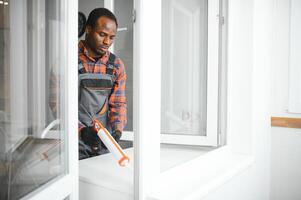 Arbeiter im Overall Installation oder einstellen Plastik Fenster im das Leben Zimmer beim Zuhause foto