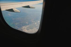 Blick durch Fensterflugzeuge während des Fluges im Flügel mit einem schönen blauen Himmel foto