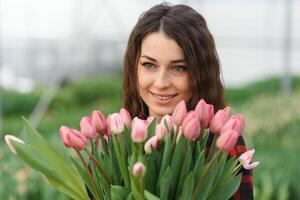 Bewässerung Blume mit Garten Schlauch während Arbeiten im Pflanze Kindergarten. selektiv Fokus. foto