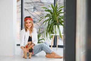 schön jung blond Frau spielen mit ihr Hund beim heim, lächelnd. Glück. foto