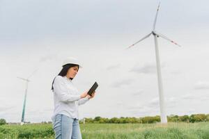 Ingenieurinnen arbeiten und halten den Bericht an der Windturbinenpark-Kraftwerksstation auf dem Berg, Thailand-Leute foto