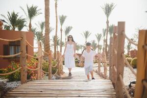 glücklich liebend Mutter und Sohn. Familie gehen in der Nähe von Palmen. Truthahn Strand Hotel. Sommer- Zeit zusammen, Sonne Licht. glücklich Mütter Tag. foto