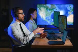 im Überwachung Zimmer technisch Unterstützung Spezialist spricht in Headset. seine Kollegen sind Arbeiten im das Hintergrund foto