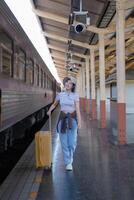 jung Frau mit Koffer wartet beim das Metro Bahnhof während das Zug kommt an, Tourismus und Reise im das Sommer. Urlaube zum das Student. Arbeit und Reise foto