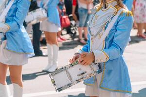 Straße Performance von festlich März von Schlagzeuger Mädchen im Blau Kostüme auf Stadt Straße. Nahansicht von weiblich Hände Schlagzeuger sind Klopfen im das Trommel von ihr Stöcke foto