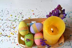 bunt Ostern Eier mit Blumen und Gelb Kerze im das Korb. schön Ostern Hintergrund. Ostern Karte. hausgemacht Urlaub Dekor. foto