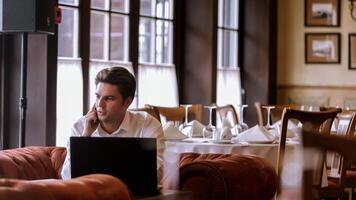 Porträt von gut aussehend Mann Sitzung beim Tabelle im Restaurant mit Laptop Computer foto