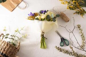 Frühling Strauß von Blumen. Schwertlilien, Tulpen, Mimose und Eukalyptus. Gelb und Blau Blume. Knospe Nahansicht. Blumen- Hintergrund. lila Iris, Weiß doppelt Tulpe. März Stimmung. foto