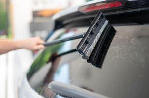 reifen männlich Arbeiter Reinigung Auto Windschutzscheibe mit das Schwamm Mopp. foto