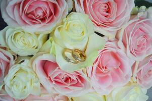 Hochzeit Ringe Lügen auf Blume Blütenblätter im ein Hochzeit Strauß von Rosa und Weiß Rosen. Hintergrund foto