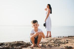 glücklich Mutter und Sohn gehen entlang das Ozean Strand haben großartig Familie Zeit auf Ferien auf Pandawa Strand, Bali. Paradies, reisen, Ferien Konzept foto