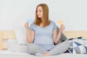 schwanger Frau im Bett im das Schlafzimmer halten ein Frage Karte, Junge oder Mädchen. foto