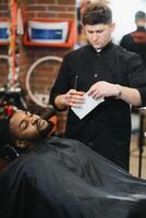 Besuch Friseurladen. afrikanisch amerikanisch Mann im ein stilvoll Barbier Geschäft foto