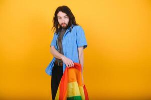 Fröhlich Mann halt Regenbogen gestreift Flagge isoliert auf farbig Hintergrund Studio Porträt. Menschen Lebensstil Mode lgbtq Konzept foto