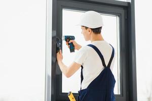 Arbeiter im Overall Installation oder einstellen Plastik Fenster im das Leben Zimmer beim Zuhause foto