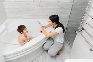 Mutter Waschen wenig Sohn im Badezimmer foto