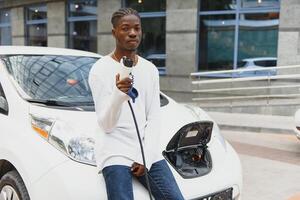 afrikanisch amerikanisch Mann Laden seine elektrisch Wagen. foto