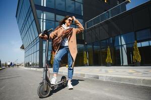 jung Frau auf das elektrisch Roller auf das Hintergrund von Büro Gebäude, Roller foto