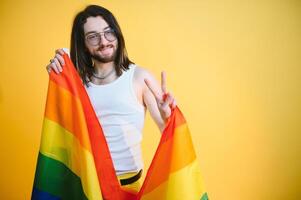 Fröhlich Mann halt Regenbogen gestreift Flagge isoliert auf farbig Hintergrund Studio Porträt. Menschen Lebensstil Mode lgbtq Konzept foto