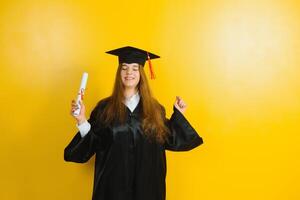 glücklich attraktiv Absolvent im ein Meister Kleid, mit ein Diplom auf ein Gelb Hintergrund. Konzept von das Abschluss Zeremonie foto