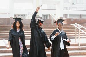 Ausbildung, Abschluss und Menschen Konzept - - Gruppe von glücklich International Studenten im Granatwerfer Bretter und Junggeselle Kleider mit Diplome foto